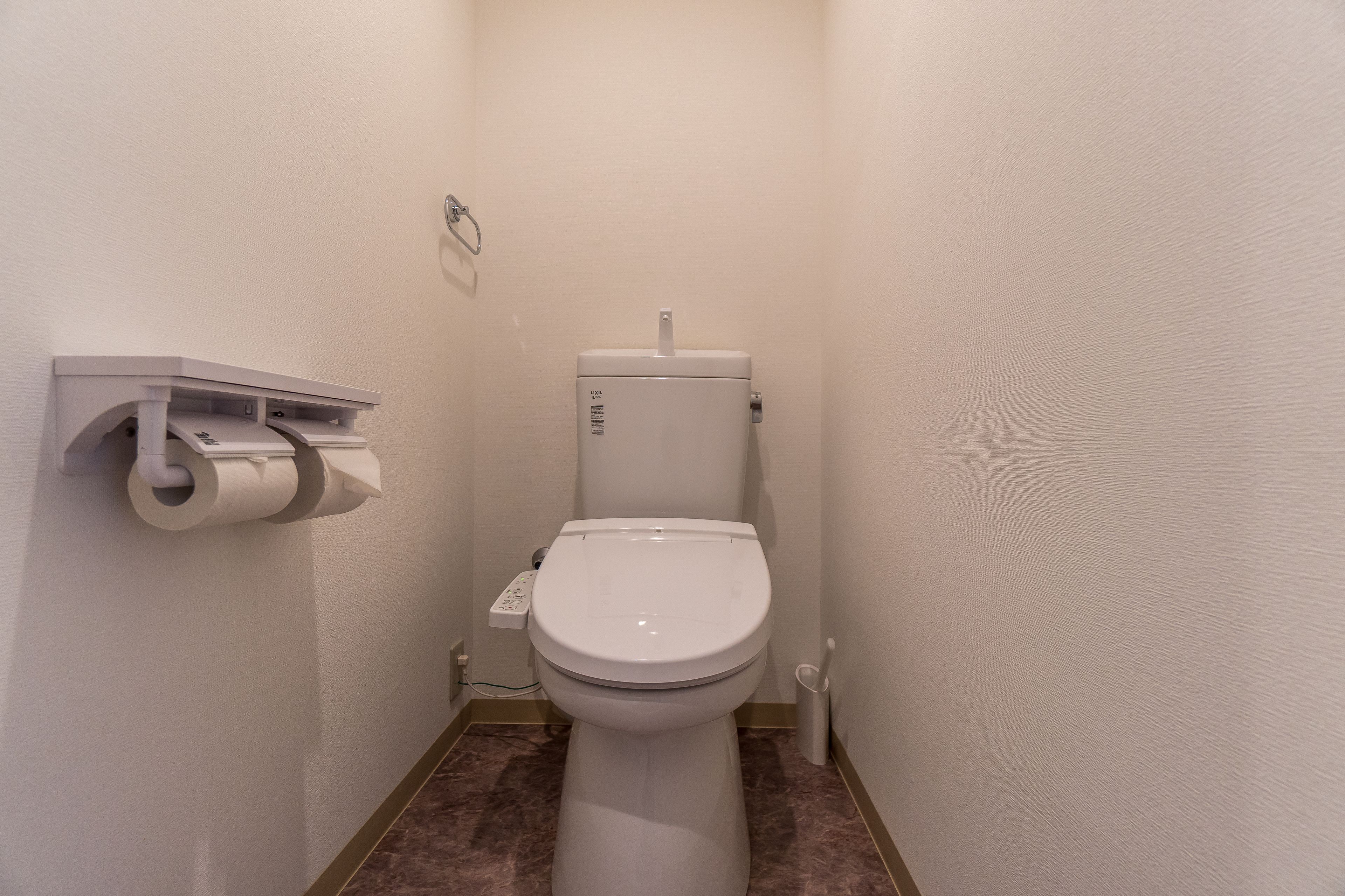 A small, narrow bathroom with a toilet, a toilet paper holder, and a bidet.
