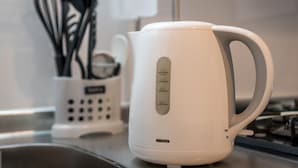 A white electric kettle with measurement markings on a kitchen counter. - Comfort Inn Kyoto (Kyoto)