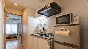 A compact kitchen with a gas stove, microwave, and refrigerator, featuring a small sink and a metal rack. - Comfort Inn Kyoto (Kyoto)