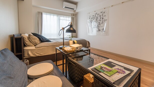 A compact hotel room with a bed, a sofa, a small table with a lamp, and a window with curtains. - Comfort Inn Kyoto (Kyoto)