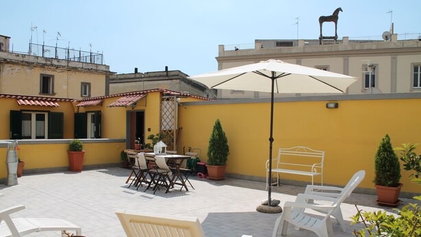 A patio with outdoor furniture, a table, and potted plants.