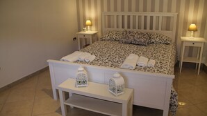 A neatly made bed with patterned bedding, two bedside lamps, and a bench with decorative lanterns.