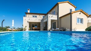 Ett tvåvåningshus med en pool framför.