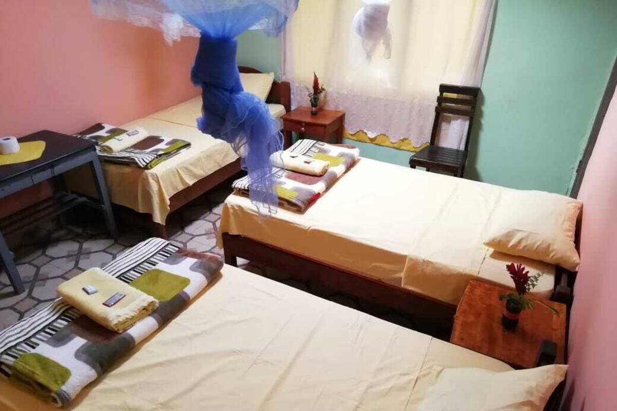 Habitación de hotel con dos camas, una mesita y una silla.