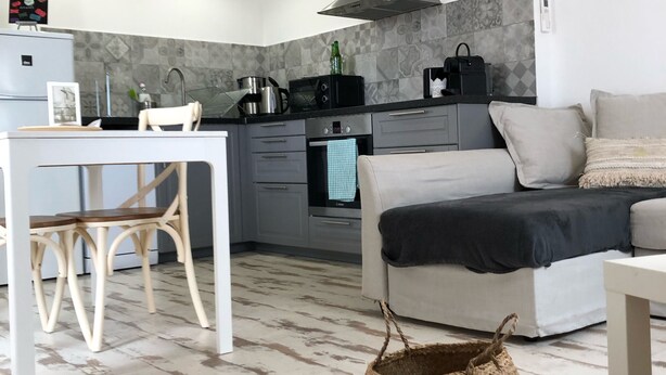 Una cocina moderna con comedor, sofá y una cesta tejida en el suelo.