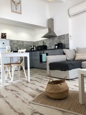 A modern kitchen with a dining area, a sofa, and a woven basket on the floor. - Le Bohème apartment, in village center, 300m from the sea, pets welcome  (LES SAINTES MARIES DE LA MER)