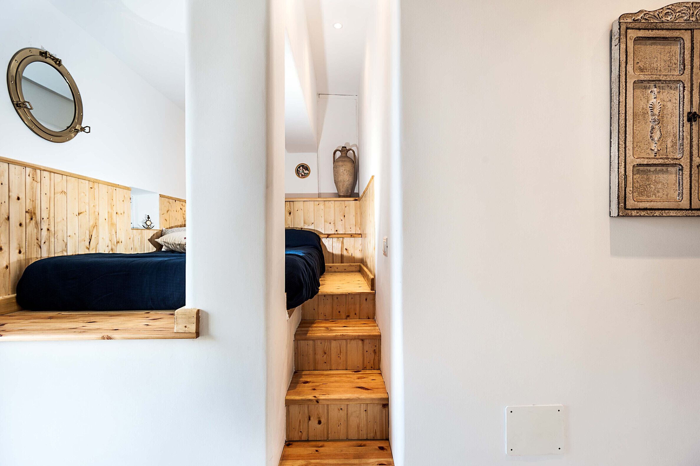 A narrow staircase with wooden steps leading to a bedroom with a bed and a small table.
