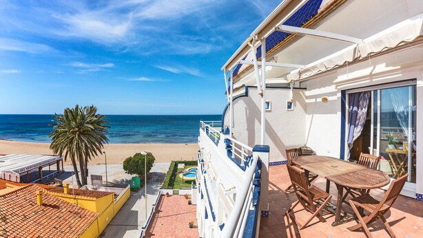 Ein Balkon mit Blick auf den Strand, einen Pool und eine Essgelegenheit mit Gartenmöbeln.