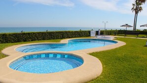 Ein Pool mit geschwungenem Design, umgeben von gepflegtem Rasen und einer Hecke.