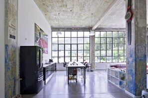 A spacious kitchen with a large window, a refrigerator, and a dining table.