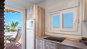 Eine Küche mit Holzausstattung, einem eingebauten Backofen und einem Fenster mit Jalousien.