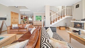 A spacious living room with leather sofas, a wooden coffee table, a fireplace, and a staircase. - 17°West – Holiday villa (option with heated pool) (Estreito da Calheta)