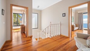 A spacious room with wooden flooring, a white staircase, and a view of the outdoors. - 17°West – Holiday villa (option with heated pool) (Estreito da Calheta)