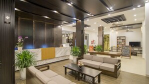 Un vestíbulo moderno con mostrador de recepción, sofás, una mesita de café y una estantería.
