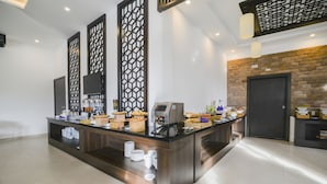 Un moderno vestíbulo de hotel con una recepción, zona de buffet y una pared decorativa de ladrillo.