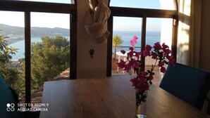 A dining area with a table and chairs, a vase of flowers, and a view of the sea through arched windows. - Fantastic detached house with GR. South Terraces + stunning views (Almuñécar)