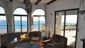 A cozy living room with a sofa, armchairs, and a coffee table. Large windows offer a view of the ocean. - Fantastic detached house with GR. South Terraces + stunning views (Almuñécar)