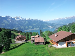 A mountain village with traditional wooden houses, a lake, and snow-capped mountains in the background. - Beatenberg, large, quiet 1 room apartment Wi-Fi / WLAN, balcony, view (Beatenberg)