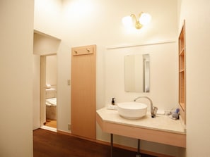 A modern bathroom with a white sink, a mirror, and a shower visible in the background.