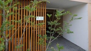 Une entrée de pièce avec un portail en bois, une pancarte indiquant « Chambre 103 », et une petite plante au premier plan.