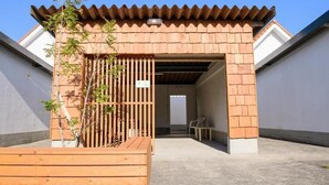 Un bâtiment doté d’une façade en bois, d’une entrée couverte et d’un banc situé au premier plan.