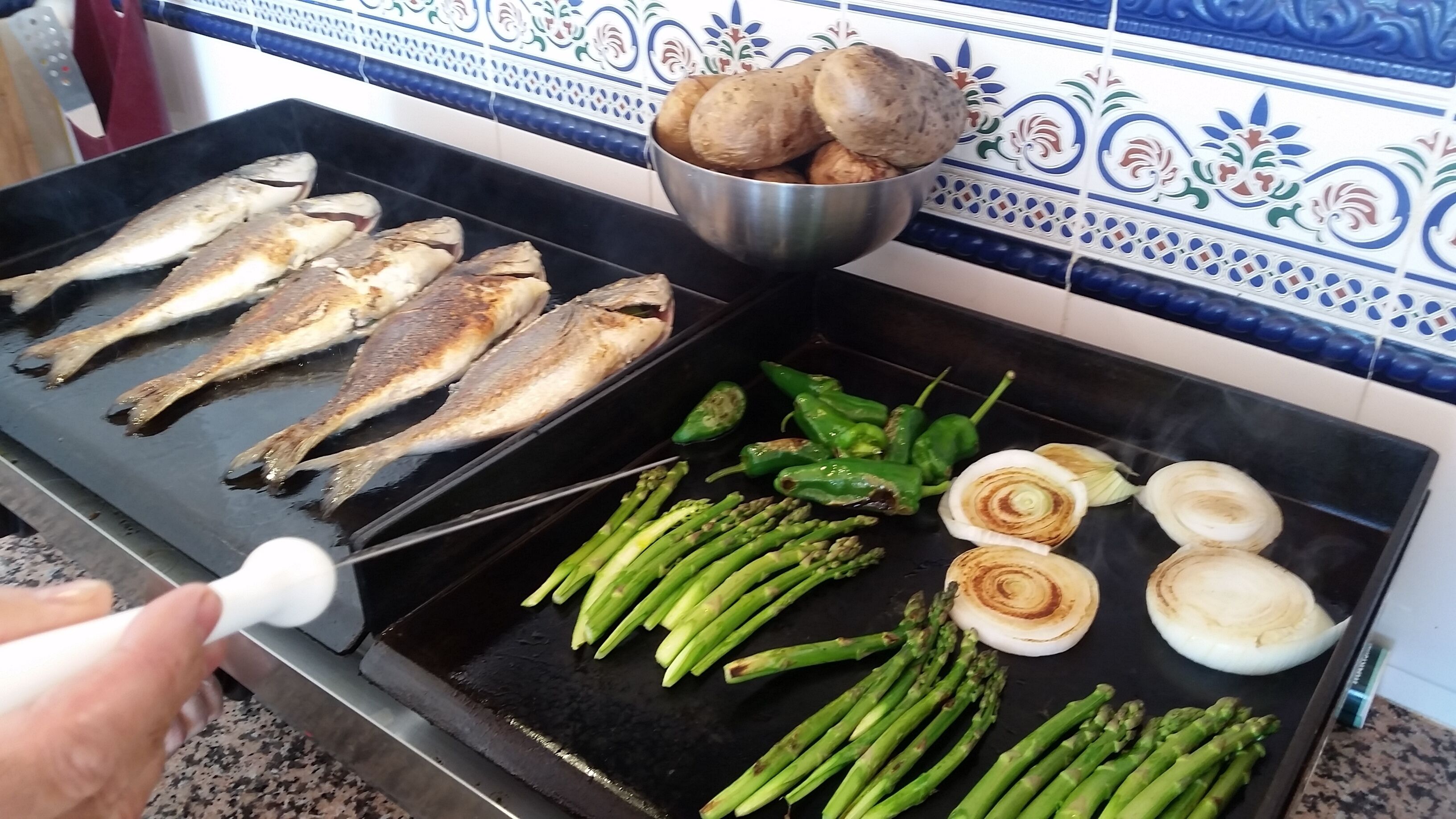 Grilled fish and vegetables on a stovetop.