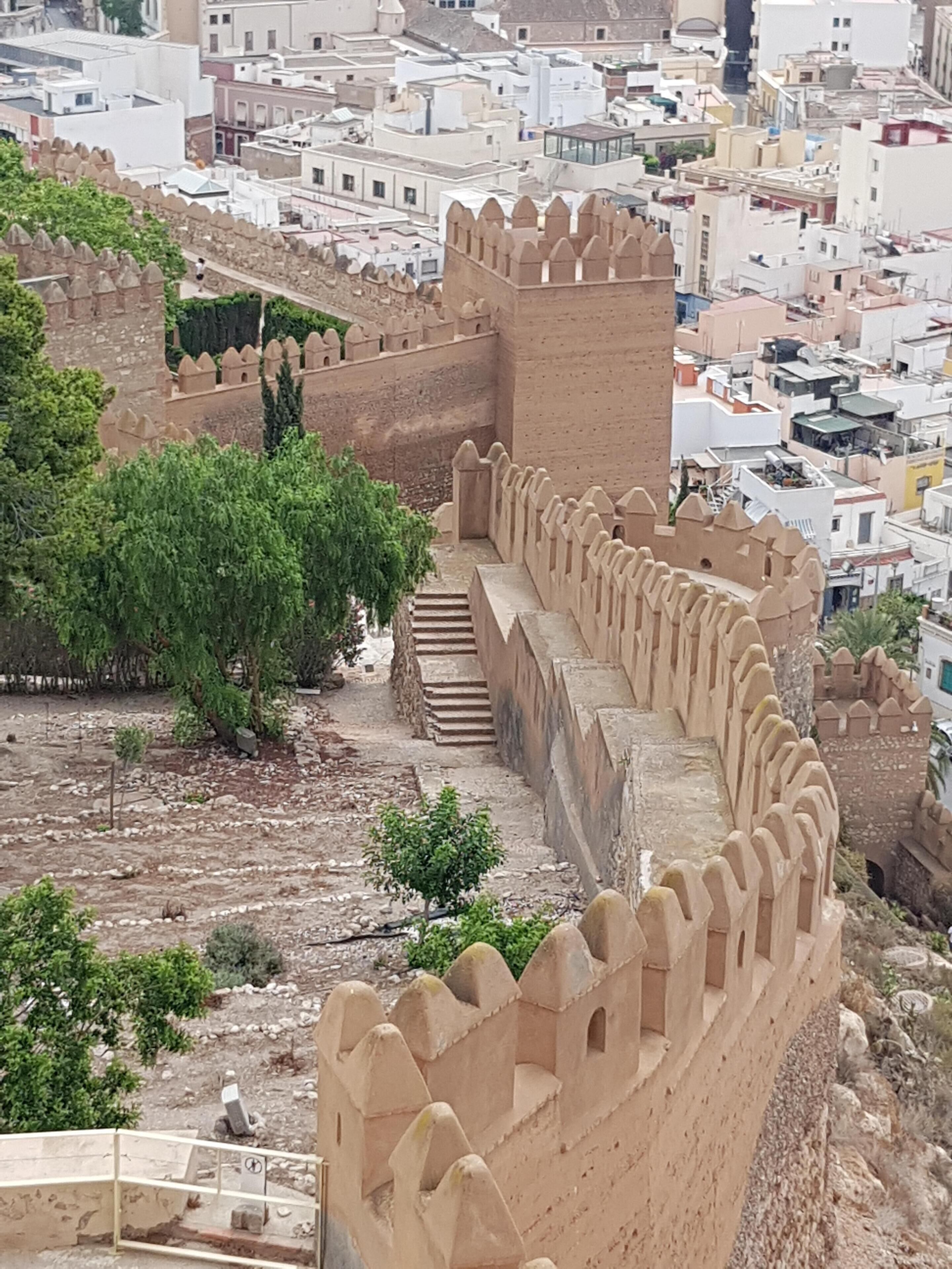 A fortified structure with a series of crenellated walls and a staircase leading up to a tower.