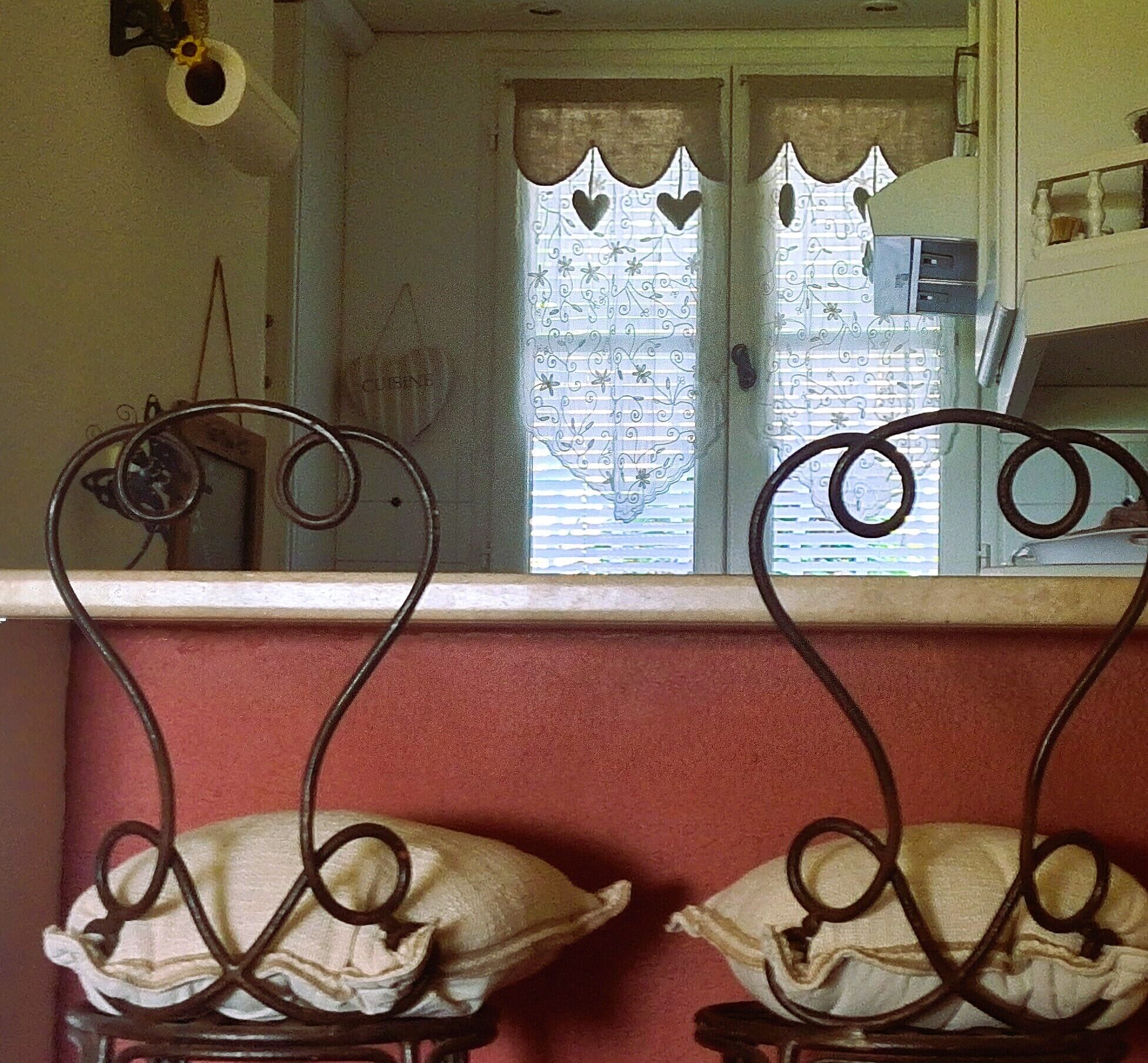 A kitchen with two double doors, a window with heart-shaped cutouts, and a metal chair with a unique design.
