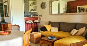 A living room with a sofa, a dining table with fruit, a wicker basket, and a mirror on the wall. - Mazet provençal with sea view, 3P air-conditioned, WiFi, terrace, garden, swimming pool (Roquebrune-Sur-Argens)