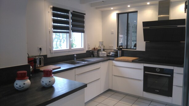 A modern kitchen with white cabinets, a black countertop, a Bosch oven, and a window with blinds. - Saint Aubin de Médoc will take place from August 22 to 29, 2026 (Saint-Aubin-De-Médoc)