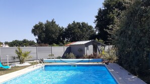 A rectangular swimming pool with clear blue water, surrounded by a tiled deck. There is a small shed with a red roof and a white fence in the background. - Saint Aubin de Médoc will take place from August 22 to 29, 2026 (Saint-Aubin-De-Médoc)
