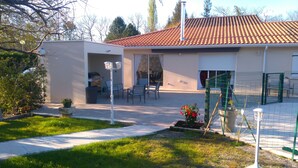 A residential building with a tiled roof, a covered patio area with outdoor furniture, and a fenced garden. - Saint Aubin de Médoc will take place from August 22 to 29, 2026 (Saint-Aubin-De-Médoc)