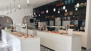 Un'area buffet con diverse postazioni di servizio, una ricca scelta di cibi e lampade a sospensione.