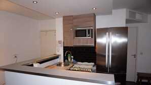 Una cucina moderna con frigorifero in acciaio inossidabile, forno a microonde e piano cottura.