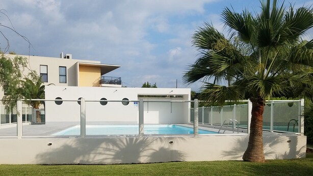 Un edificio moderno con piscina, circondato da palme e da un'area verde.