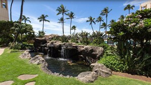A landscaped garden with a small waterfall, palm trees, and a pool area. - DIRECT Oceanfront! Amazing Panoramic View Sugar Beach 236! Refresh, Relax, Enjoy (Kihei)