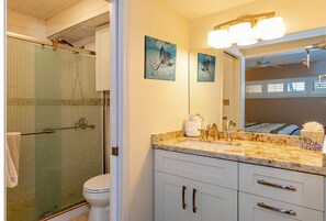 Une salle de bain avec une douche à parois de verre, des toilettes, un lavabo avec un meuble-vasque et un miroir.