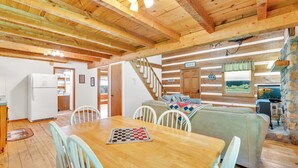 A wooden interior with a dining table, chairs, a sofa, a staircase, and a stone wall. - Creekside Bliss! Back Yard Creekside Retreat !!! (Cosby)