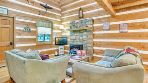A cozy cabin interior with a stone fireplace, wooden walls, and two plush armchairs. - Creekside Bliss! Back Yard Creekside Retreat !!! (Cosby)