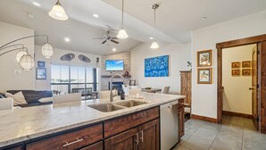 Una cocina moderna con una isla grande, electrodomésticos integrados e iluminación colgante.