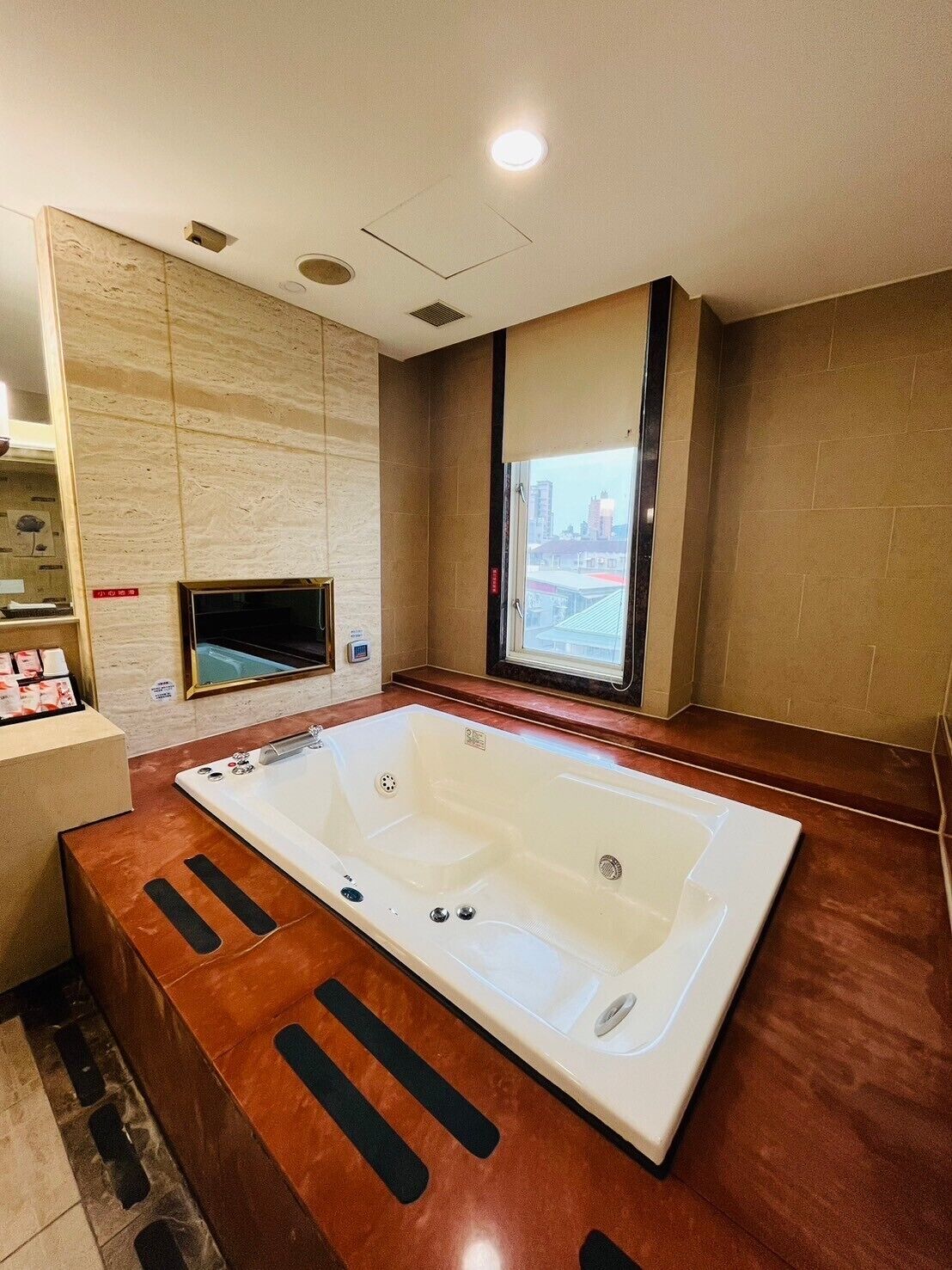 Un baño moderno con una bañera grande, una ventana con vista a la ciudad y un tocador de madera.