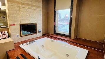 Un baño moderno con una bañera grande, una ventana con vista a la ciudad y un tocador de madera.