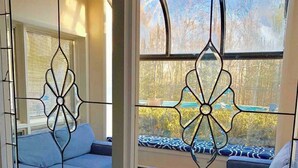 Un salón moderno con un sofá, una mesa de centro y vistas a través de una ventana con vidrio decorativo.
