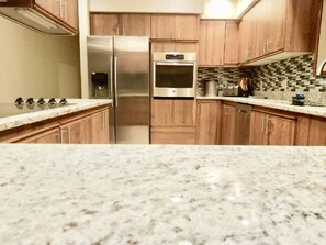 A kitchen with wooden cabinets, stainless steel appliances, and a tiled backsplash.