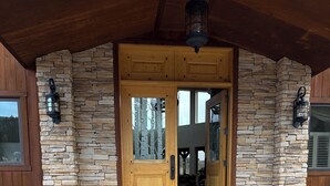 Une entrée revêtue de pierres, avec une porte en bois, des marches en pierre et une lanterne au-dessus.