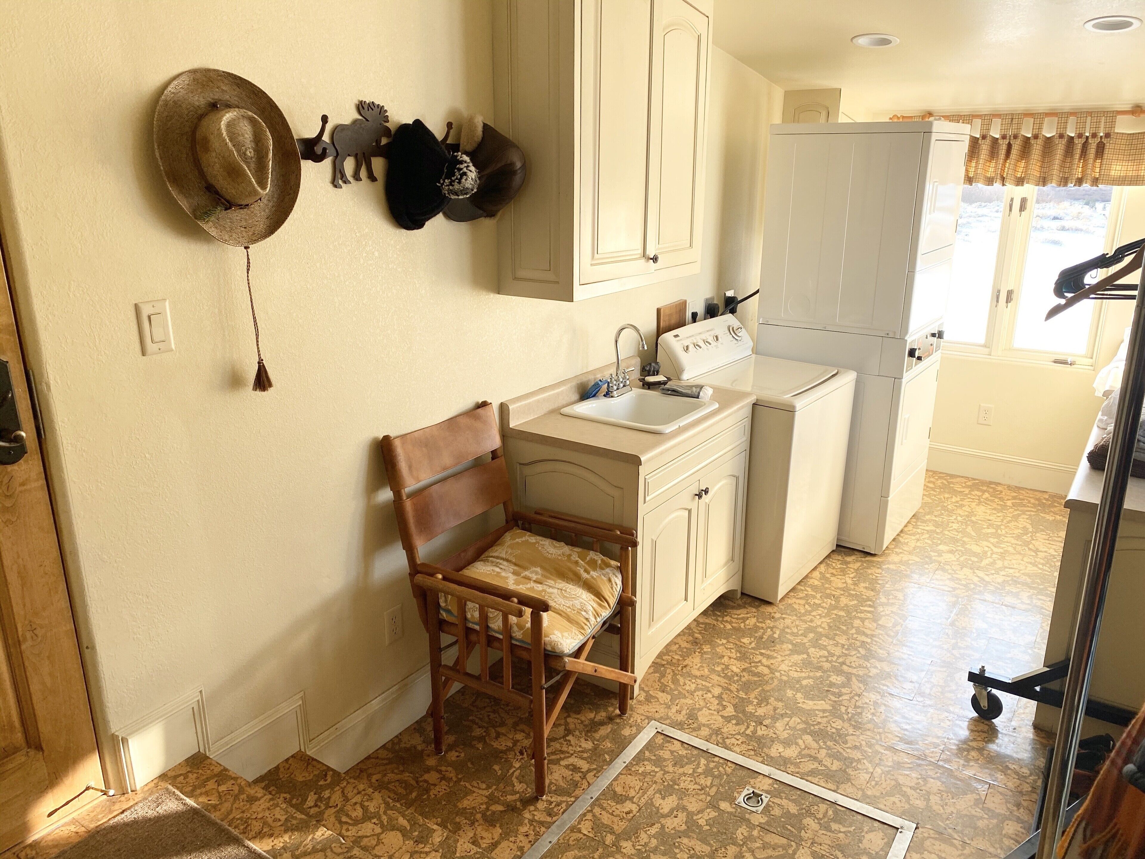 A compact kitchen with a wooden chair, a sink, a stove, and a refrigerator.