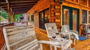 Eine Holzhütte mit einer Veranda, ausgestattet mit rustikalen Holzstühlen und einem Tisch mit Weingläsern.