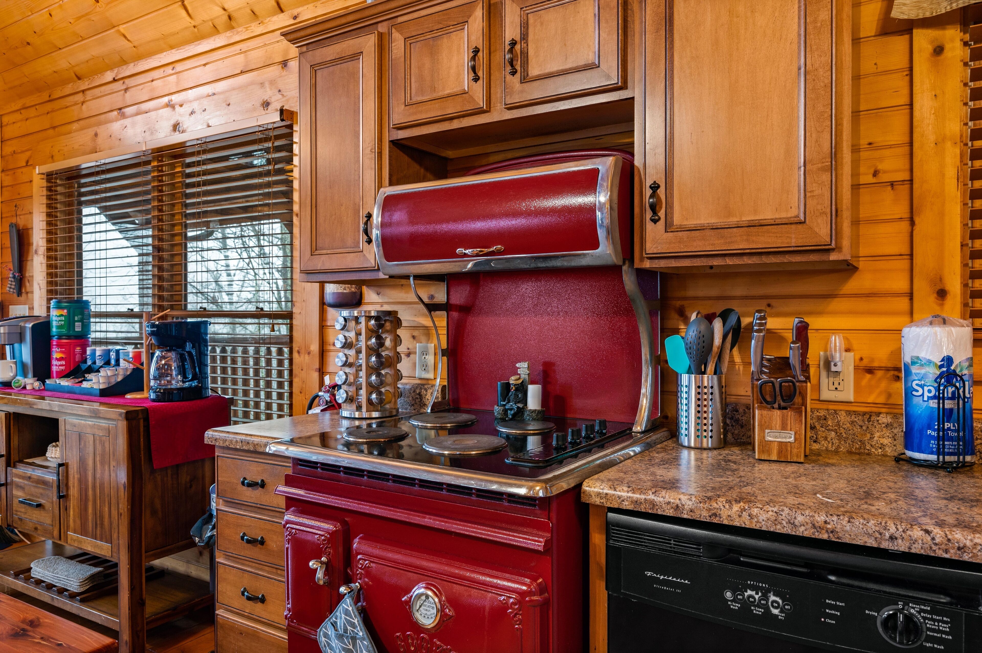 Cocina con armarios de madera, una estufa roja y diversos utensilios de cocina.