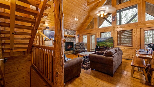 Ein rustikales Holzhaus-Interieur mit Kamin, Holzmöbeln und großen Fenstern.