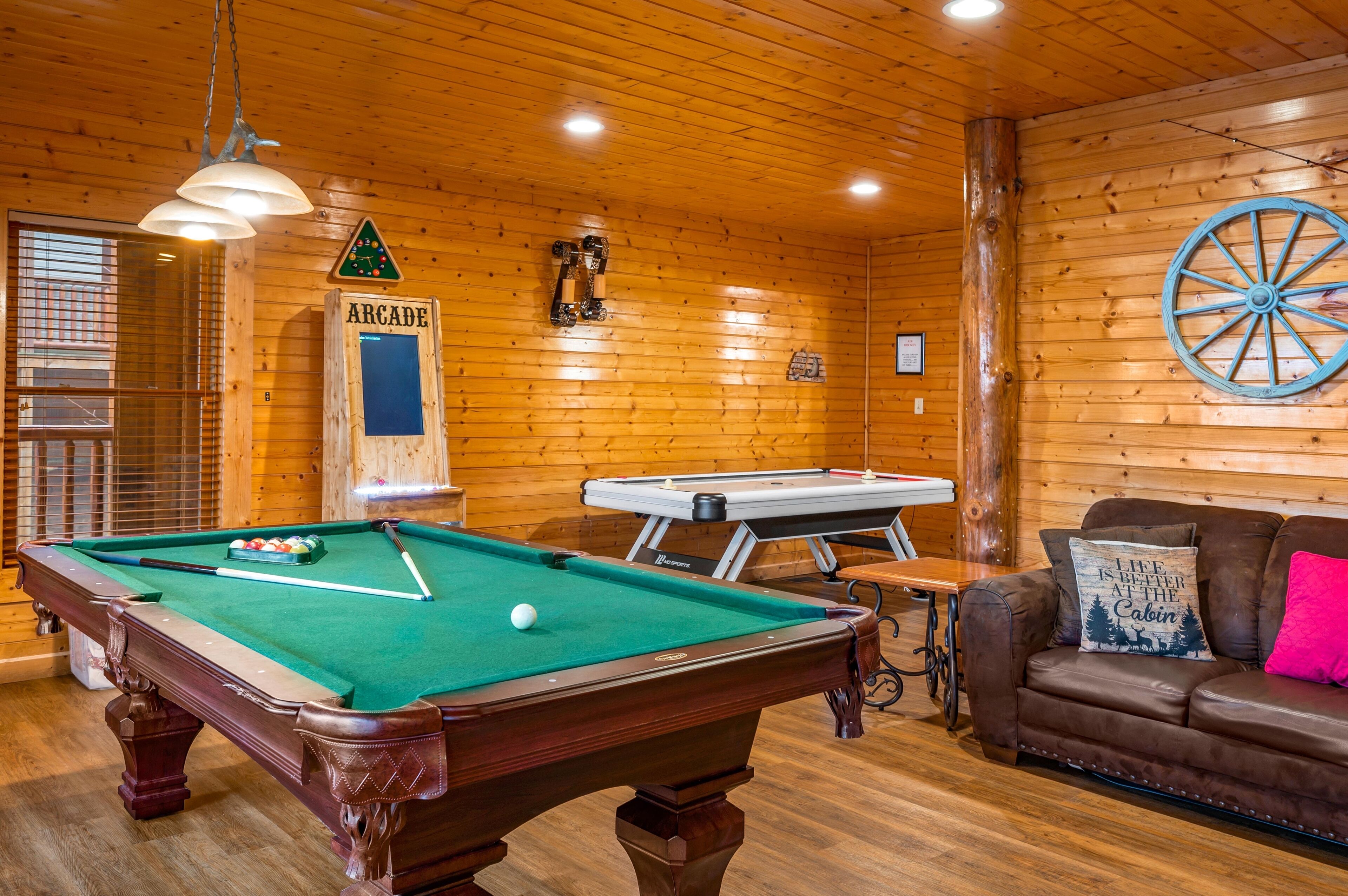 Une table de billard avec une boule blanche, une table de jeu de flipper et un mur en bois sur lequel est affiché un panneau indiquant « SALLE D’ARCADE ».
